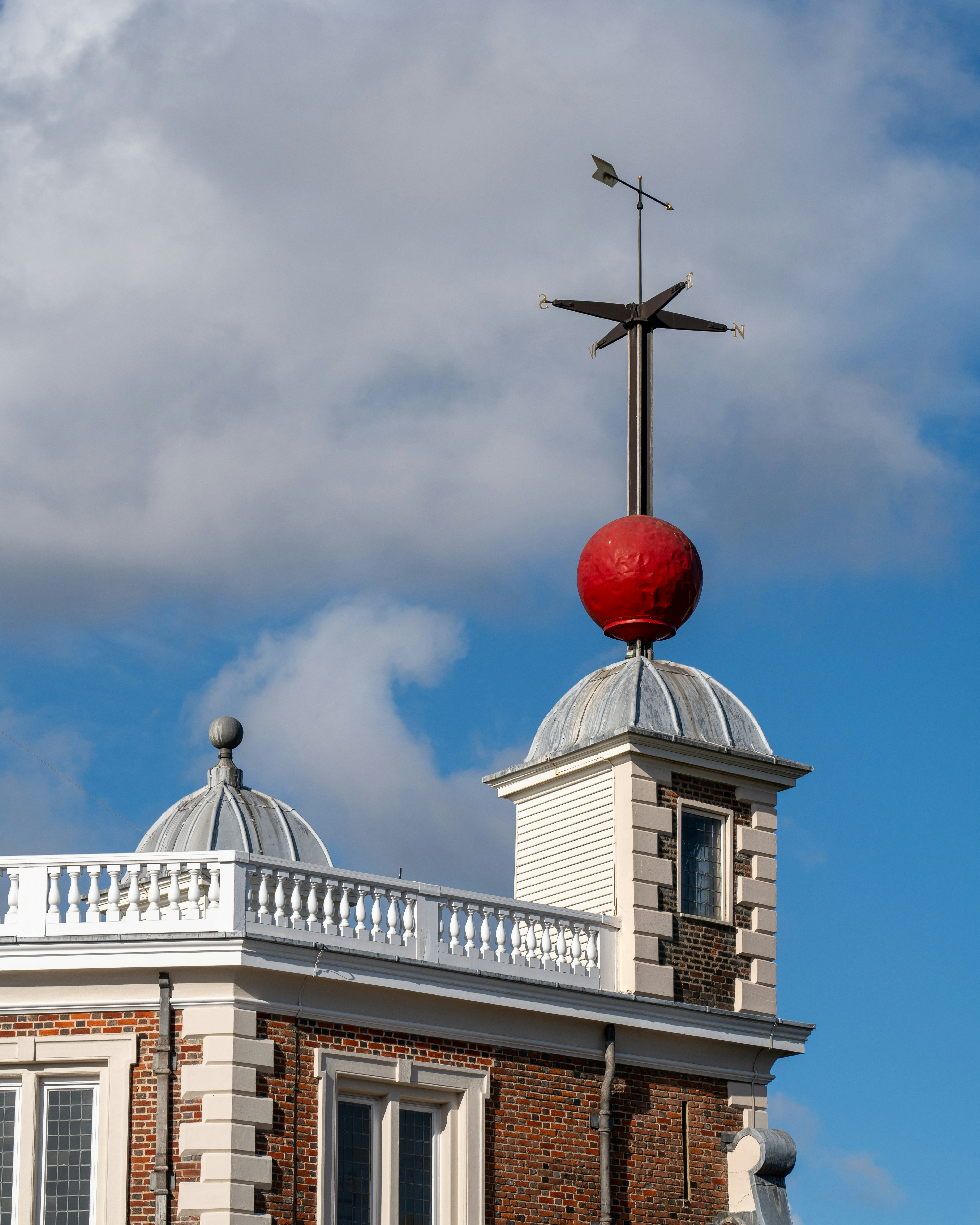 a red ball on top of a building with a cross on top