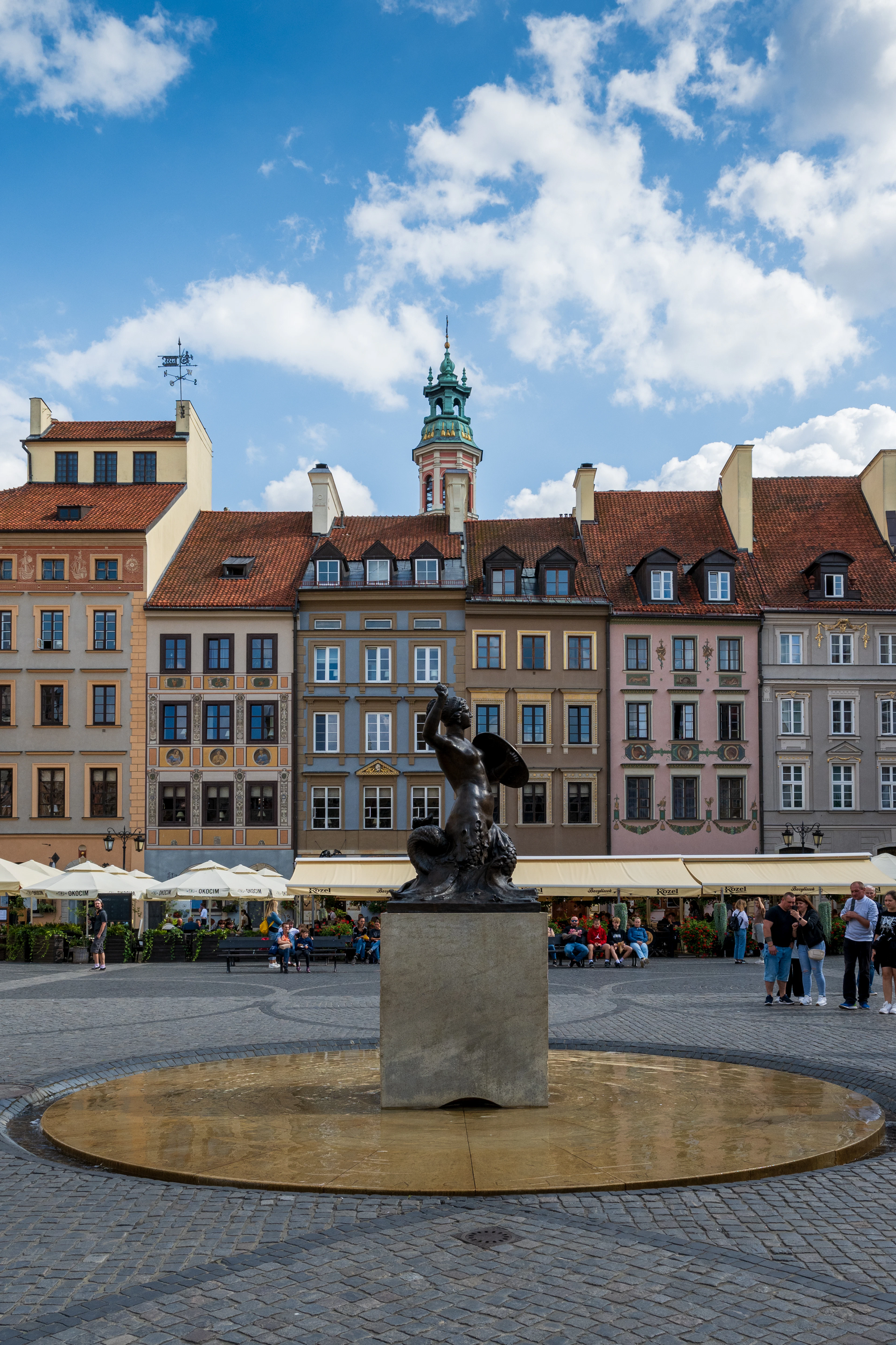 The bronze Warsaw Mermaid statue and fountain in the Old Town Market Square, ringed by colorful facades