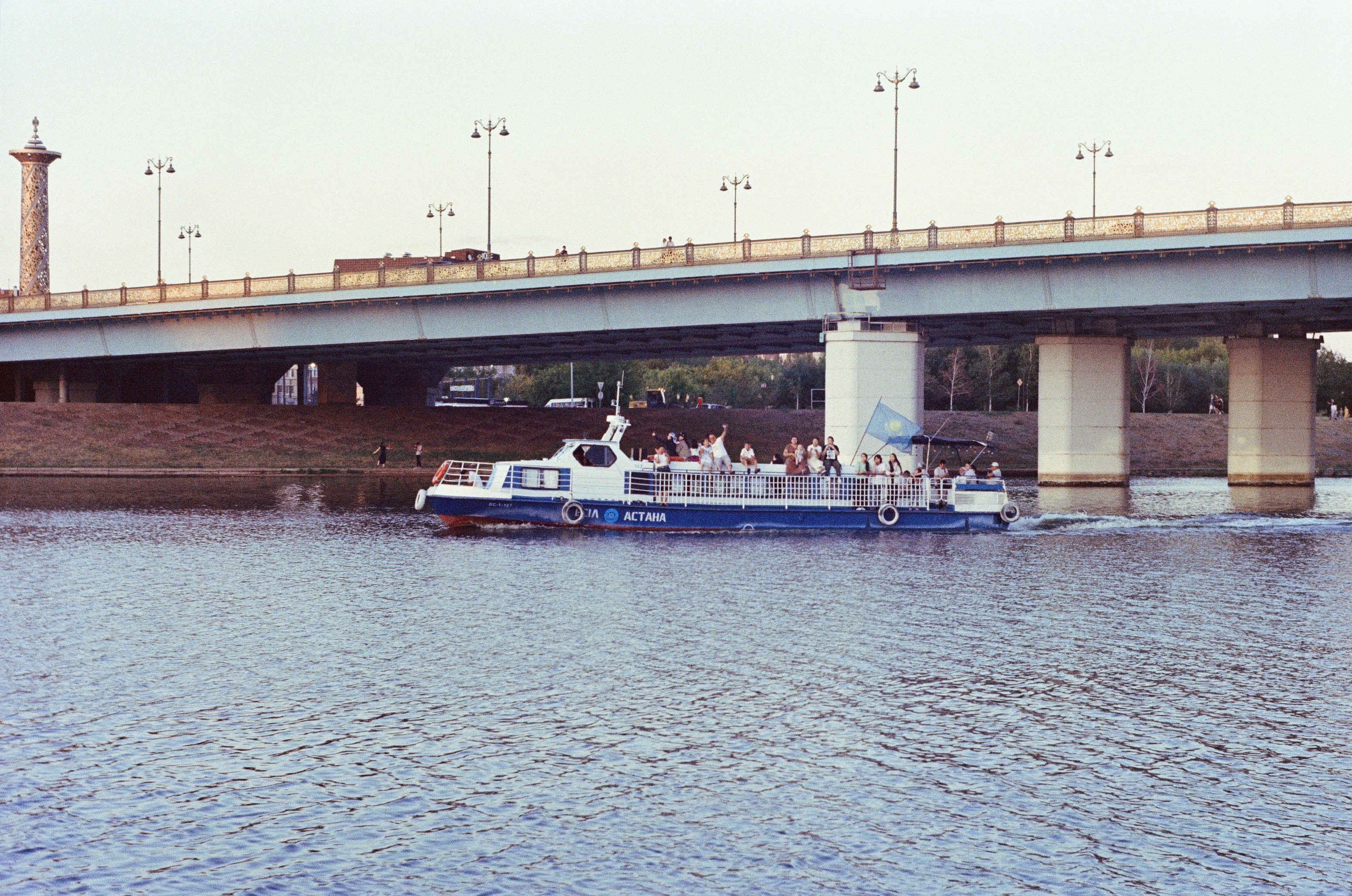 a blue and white boat traveling under a bridge