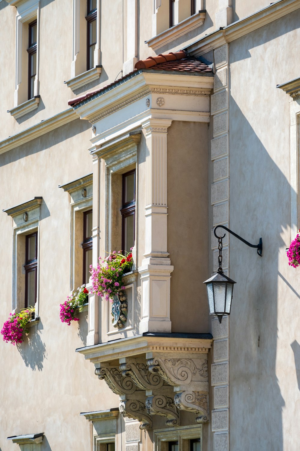 a tall building with a bunch of flowers hanging from it's windows