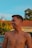 a man with no shirt on standing in front of a car