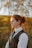 a woman in a vest and tie standing in a field