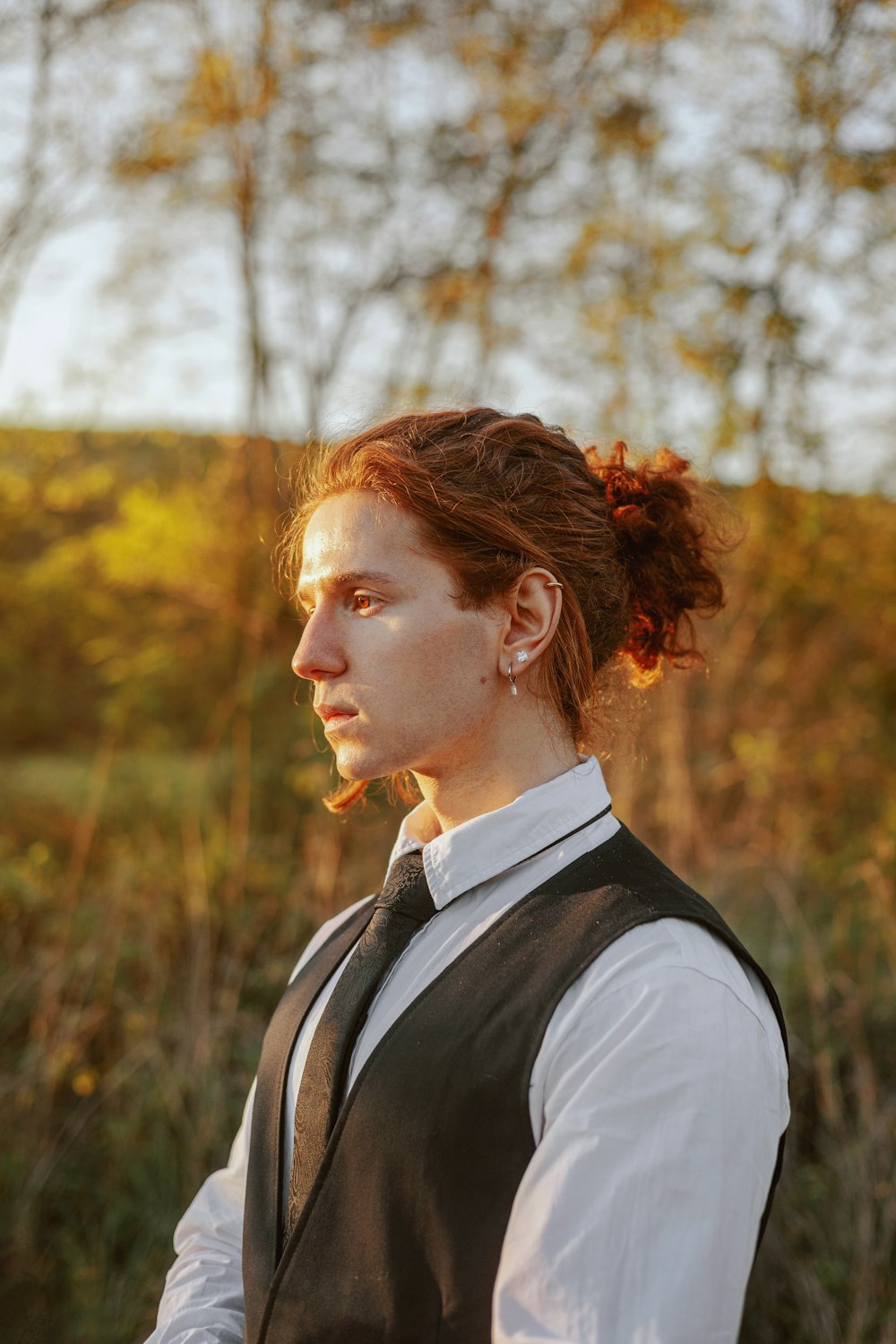 a woman in a vest and tie standing in a field