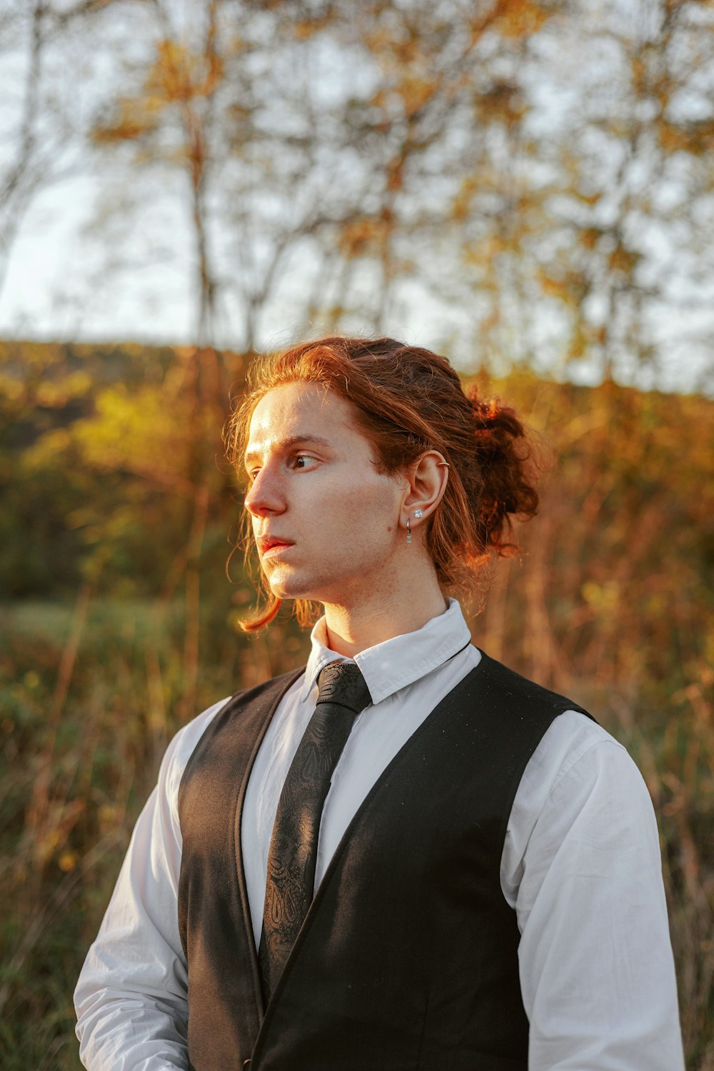 a woman in a vest and tie standing in a field