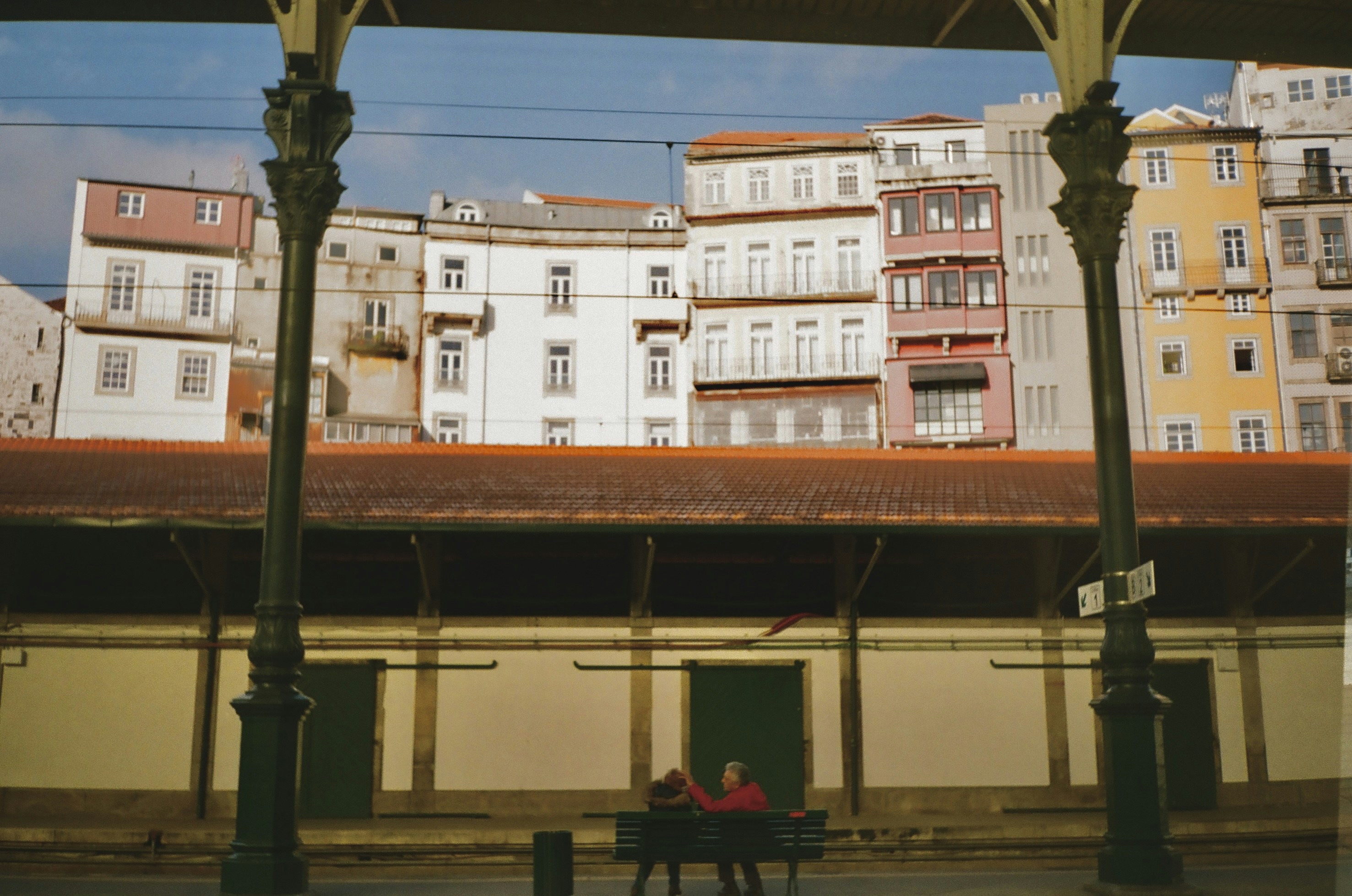 two people sitting on a bench in front of a building