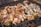 Pieces of marinated chicken are arranged on a barbecue grill, cooking over hot coals. The seasoning appears to be a mixture of herbs and spices, giving the chicken a rich, appetizing appearance.