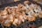 Pieces of marinated chicken are arranged on a barbecue grill, cooking over hot coals. The seasoning appears to be a mixture of herbs and spices, giving the chicken a rich, appetizing appearance.