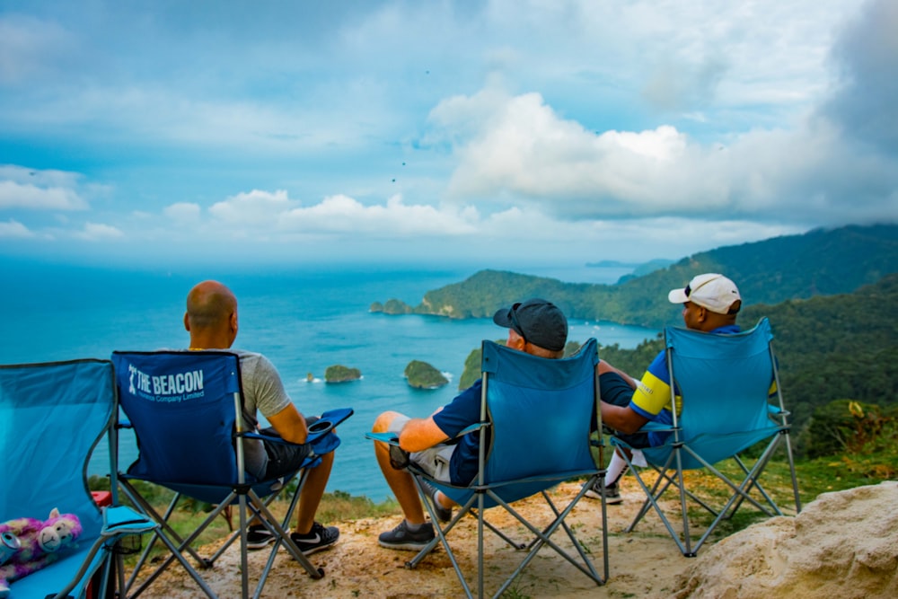 a couple of people sitting in lawn chairs on top of a hill