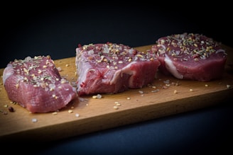 two pieces of raw meat sit on a cutting board