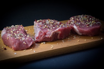 two pieces of raw meat sit on a cutting board