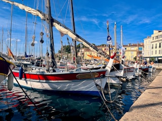 A vibrant coastal view of Essaouira with colorful boats docked at the harbor under a clear blue sky.