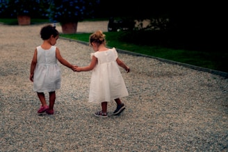 Two sisters walking barefoot on a soft earth path, holding hands