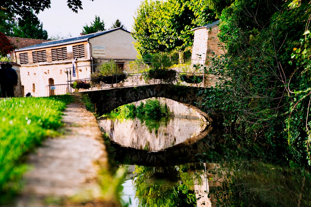 a stone bridge over a river next to a lush green field