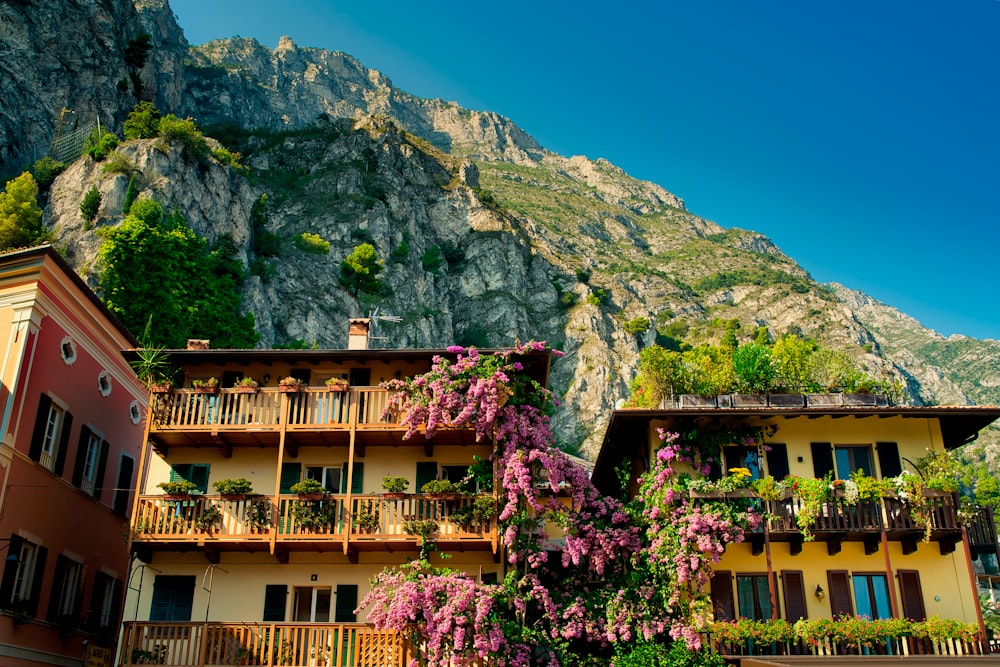 a building with balconies and flowers in front of a mountain