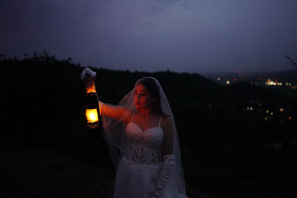 a woman in a wedding dress holding a lantern