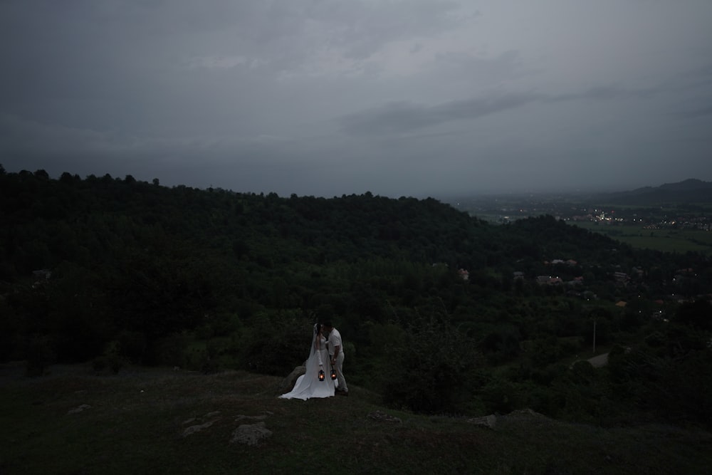 a bride and groom standing on top of a hill