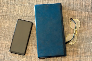 Flat lay of various handy products including a minimalist notebook, pen, and phone case on a clean white surface