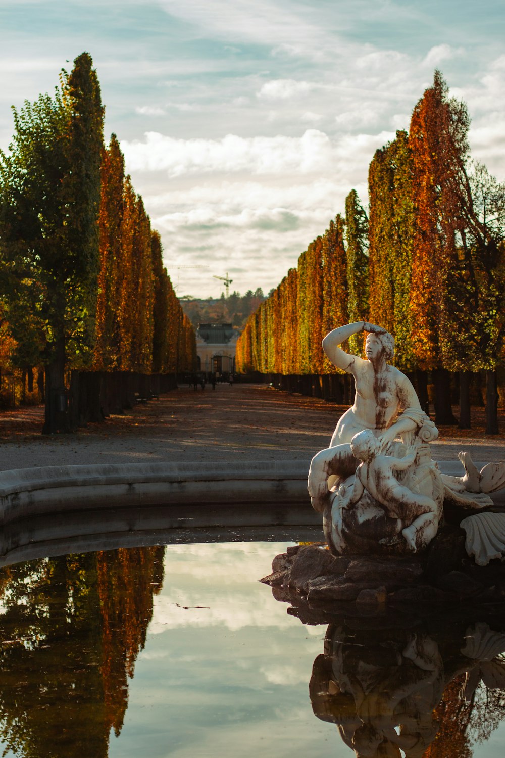 a statue sitting on top of a rock next to a pond