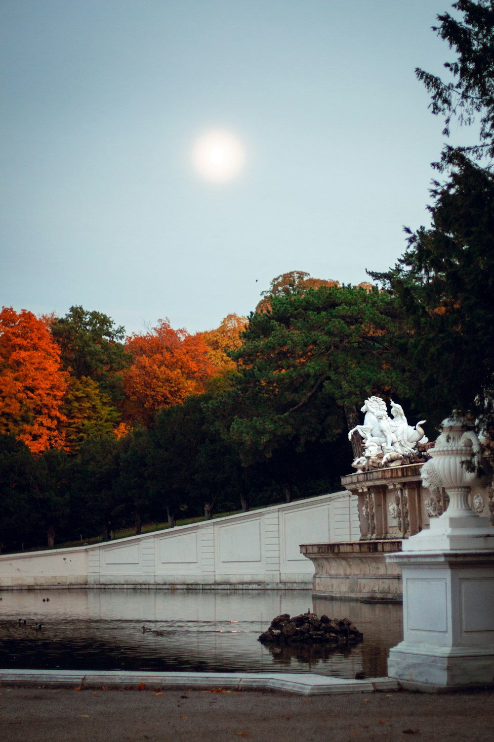 a full moon is seen in the sky above a fountain