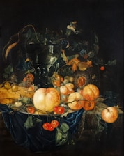 A detailed still life painting featuring various fruits such as peaches, cherries, and grapes, artfully arranged on a blue draped fabric. A dark vase filled with foliage and flowers adds depth, while a wooden container holds additional fruit. The composition includes intricate details of leaves, stems, and the textures of the fruit.