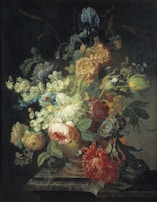 A lush arrangement of various flowers in a decorative vase. The bouquet includes blooms of different colors and types, such as roses, peonies, and irises, set against a dark background that accentuates their vibrant hues. The composition displays a natural, cascading effect with detailed foliage enhancing its intricate design.