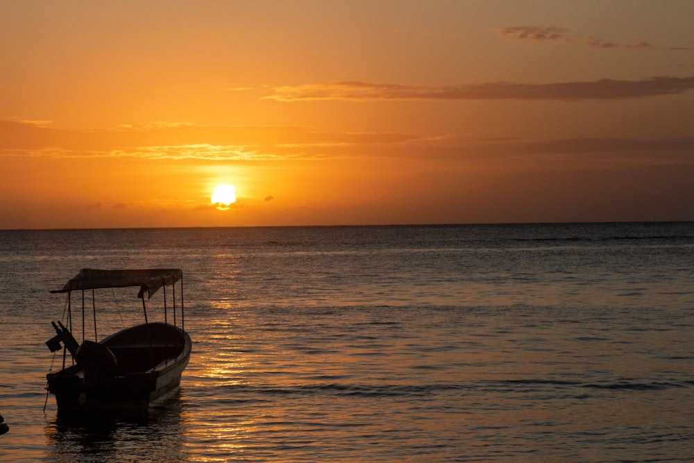 a boat in the water with the sun setting in the background