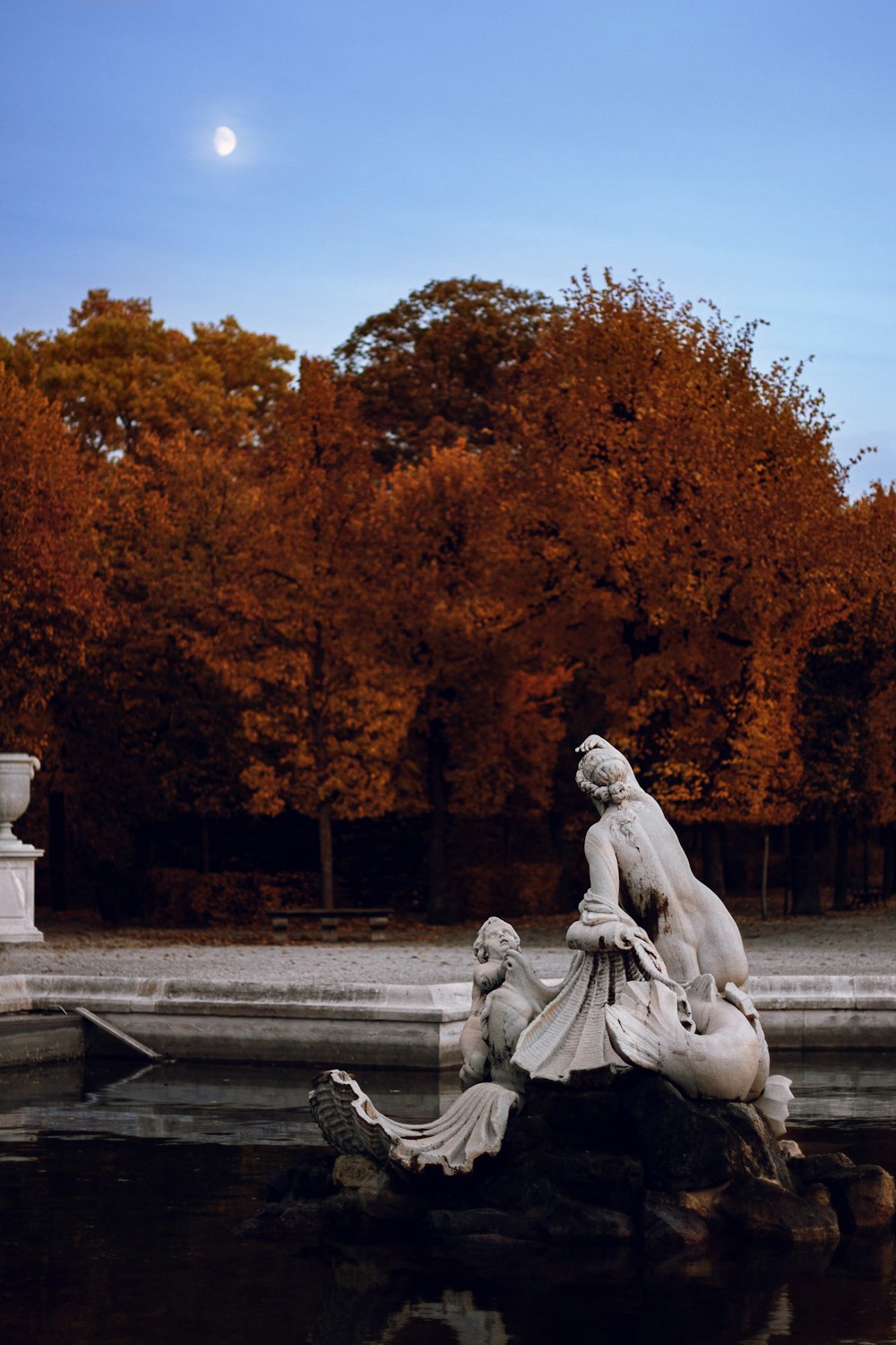 a statue sitting on top of a rock next to a body of water