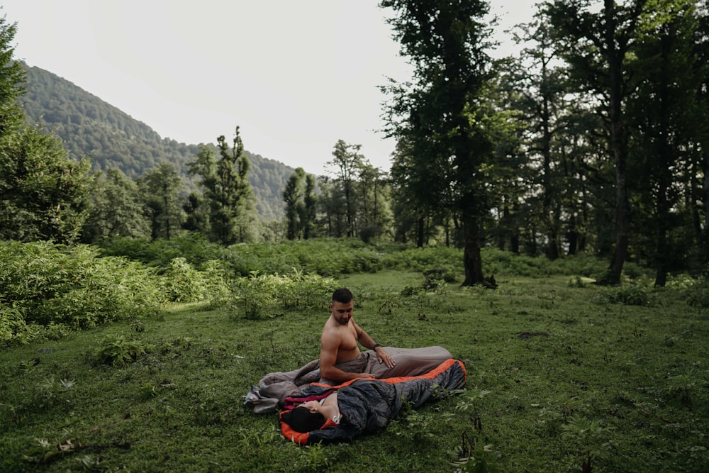 a man sitting on a blanket in the middle of a forest