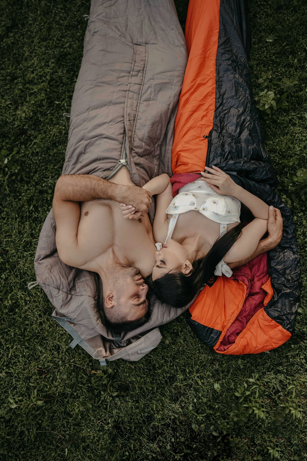 a man and a woman laying on a blanket in the grass