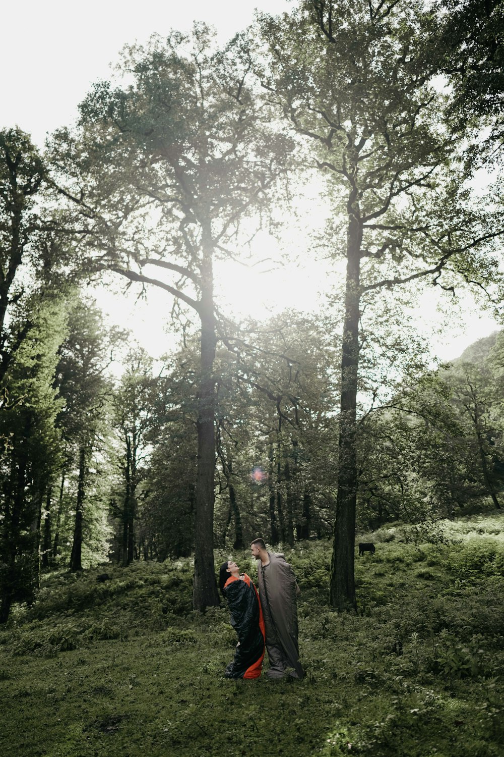 a couple of people standing next to each other in a forest