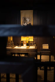 An elegant wooden desk with historical artifacts and a softly glowing lamp.