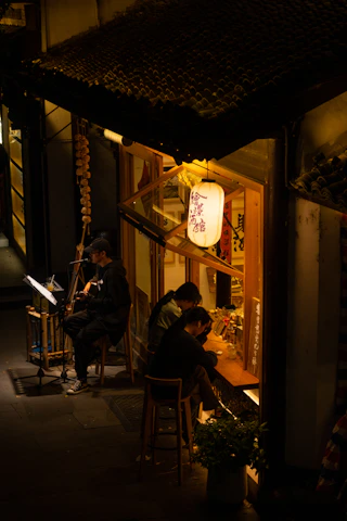 An elderly couple enjoying live blues music on a cozy porch with string lights.