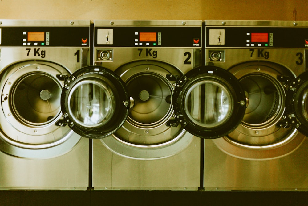 a row of washers in front of a row of dryers