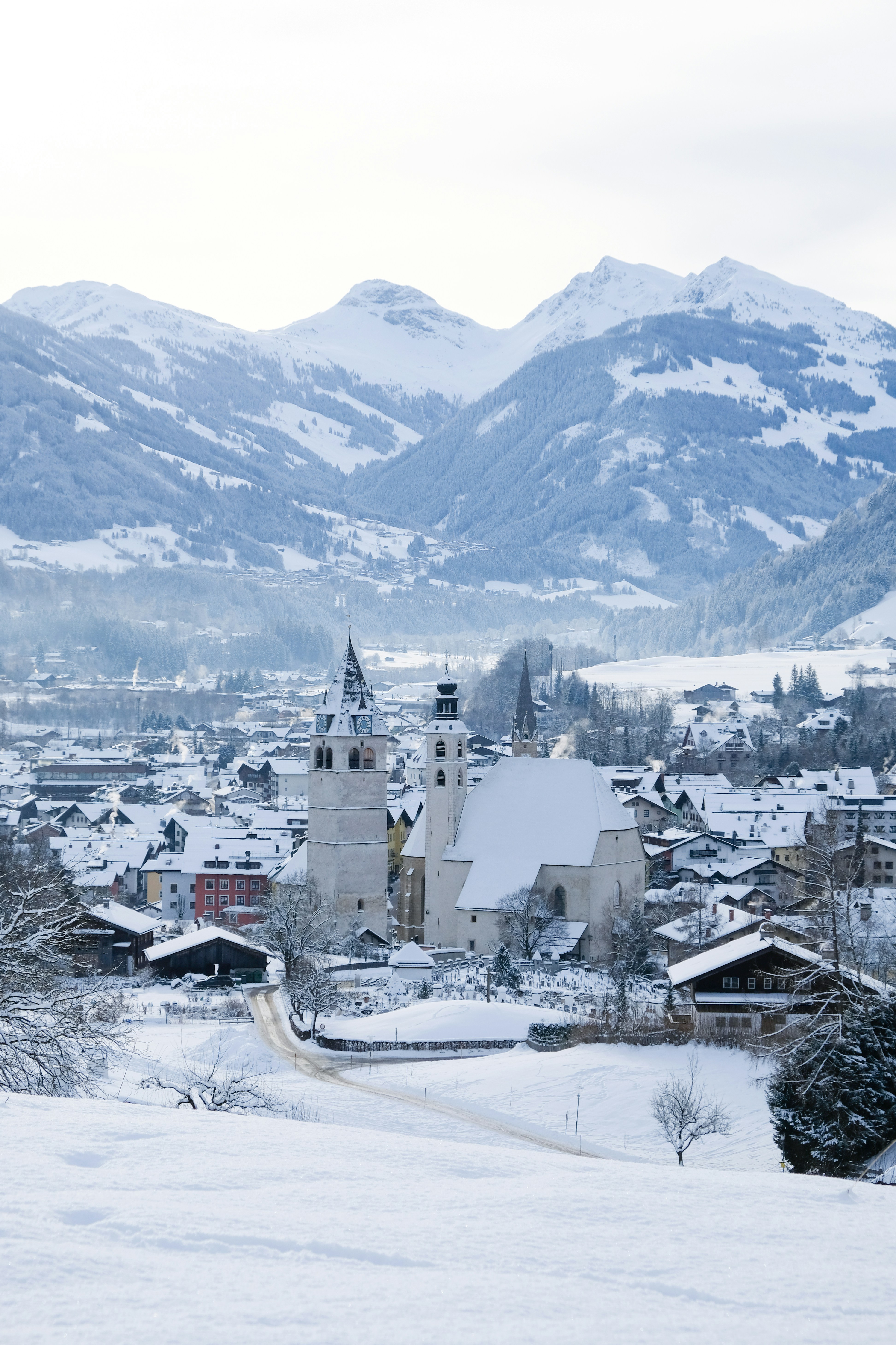a snowy town with a church and mountains in the background