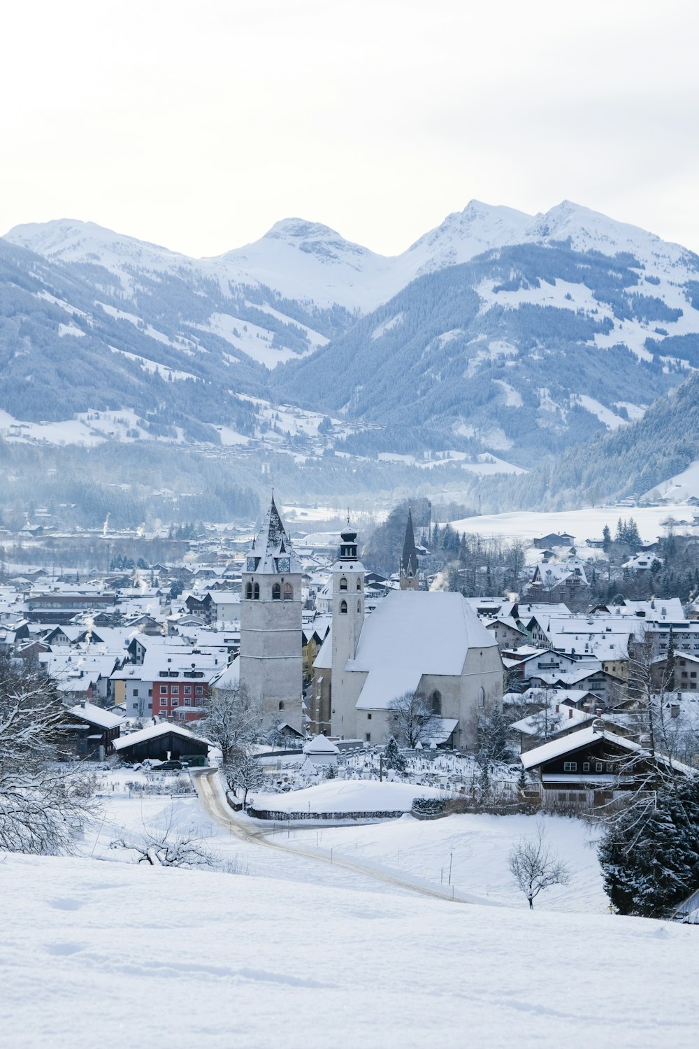a snowy town with a church and mountains in the background