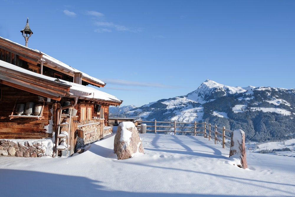 a wooden cabin in the snow with mountains in the background