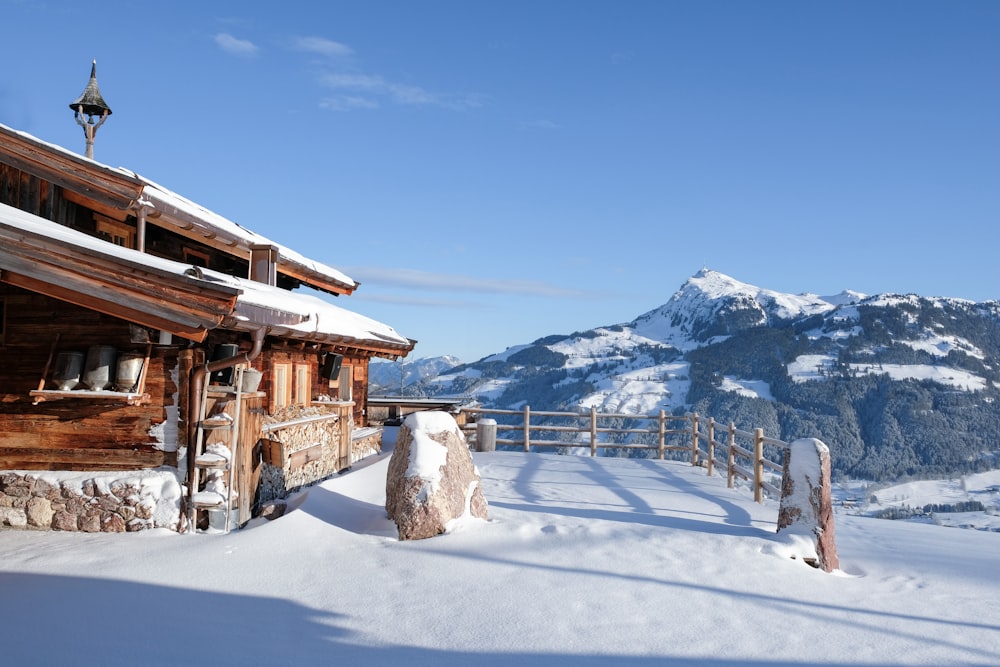 uma cabana de madeira na neve com montanhas ao fundo
