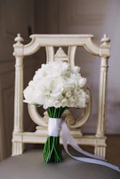 Bride’s bouquet of white roses and greenery resting on a vintage wooden bench.