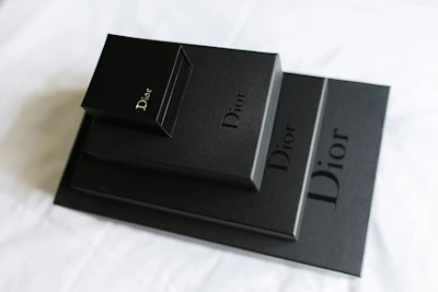 Branded packaging boxes stacked neatly, featuring bold orange accents on black matte finish.