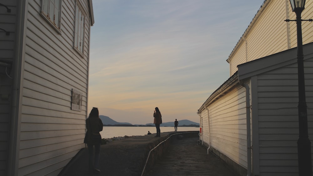 a couple of people walking down a street next to a body of water