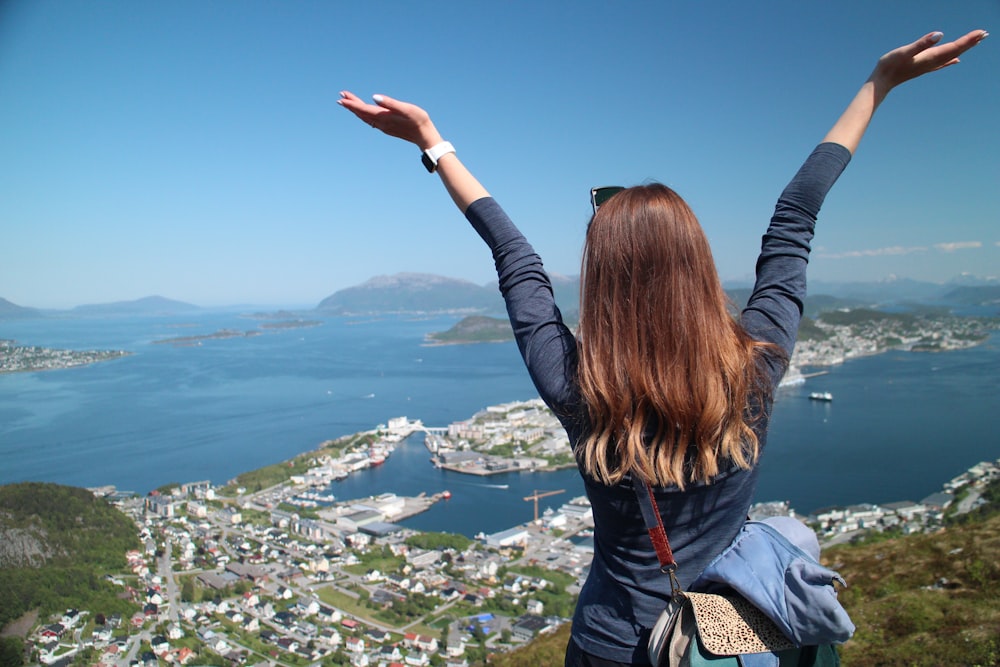 a woman standing on top of a hill with her arms outstretched