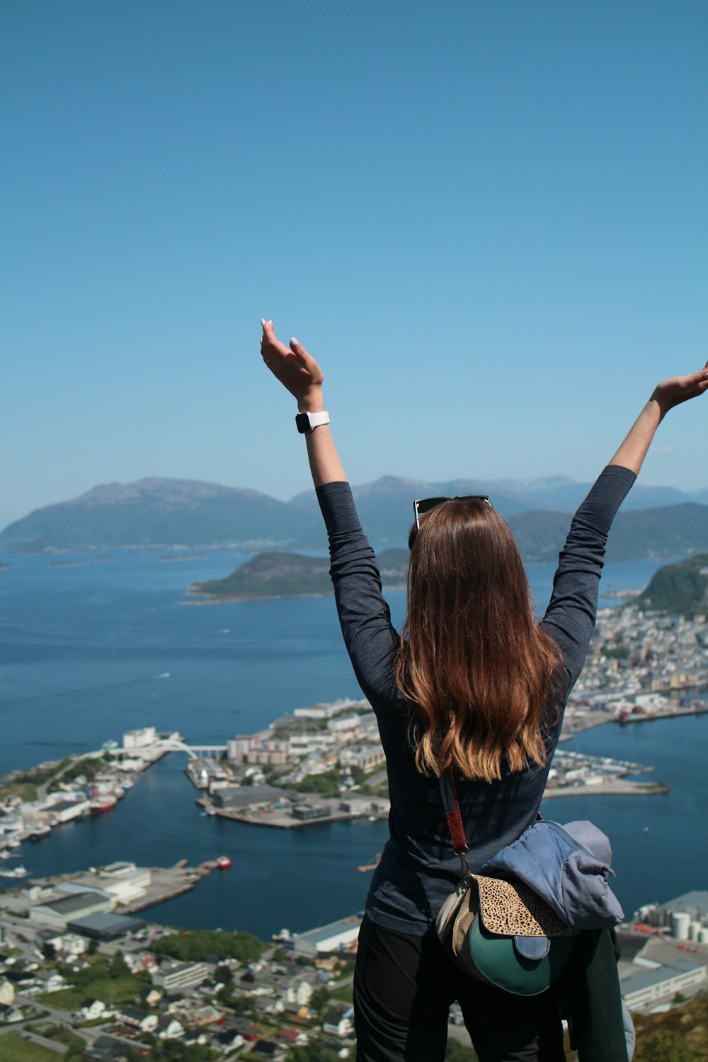 a woman standing on top of a hill with her arms in the air