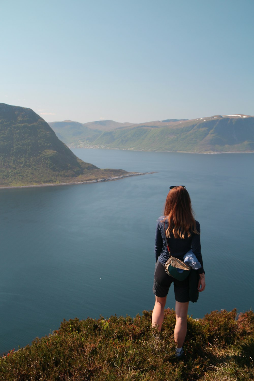 a woman standing on top of a lush green hillside