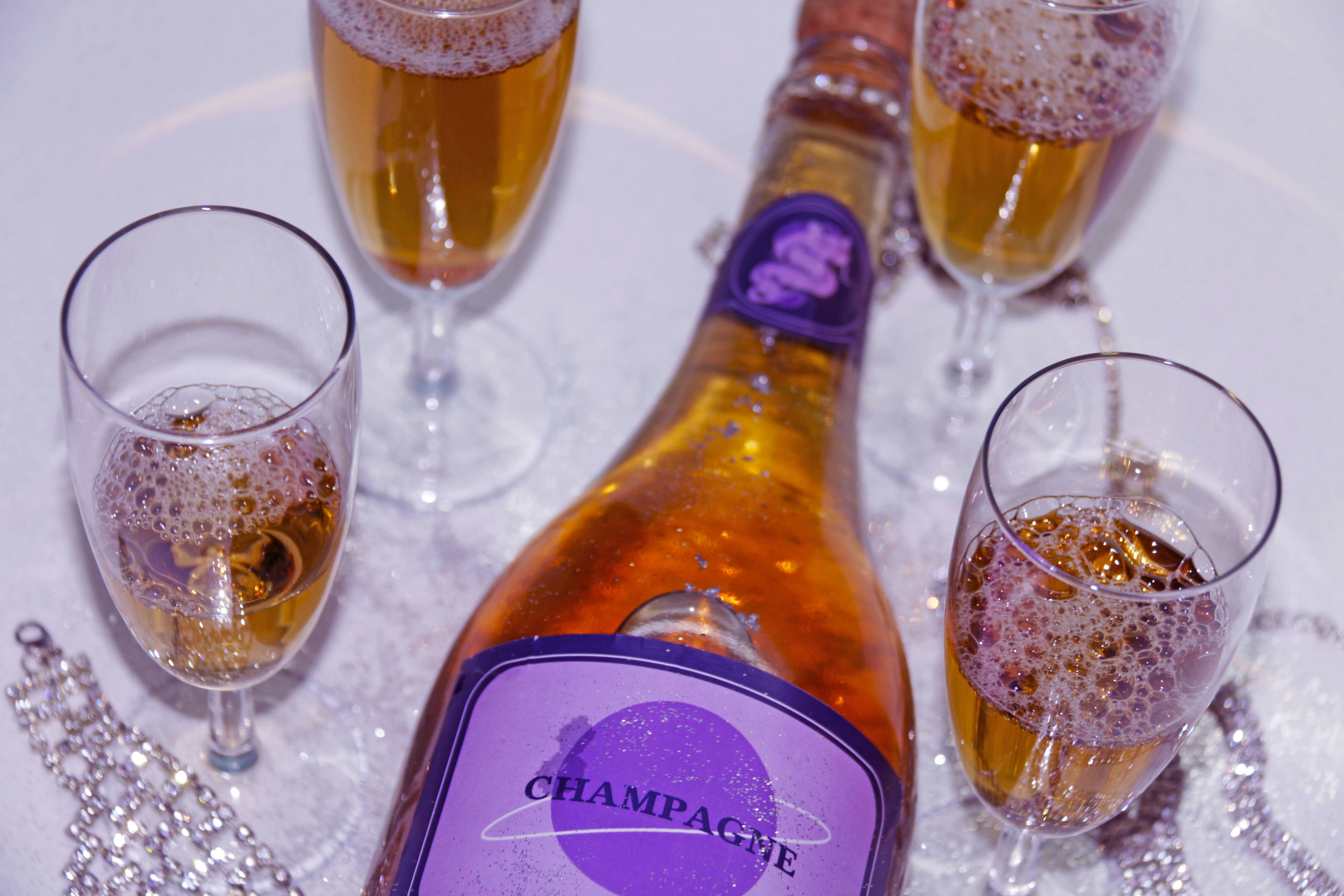 A bottle of champagne next to three glasses of champagne