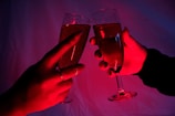 Close-up of hands holding sparkling champagne glasses with $happy coin logos
