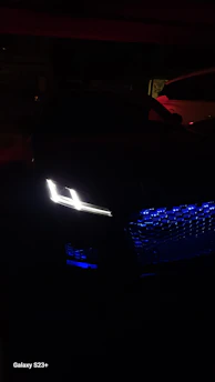 A stylish car illuminated by vibrant LED lights highlighting its contours at night.