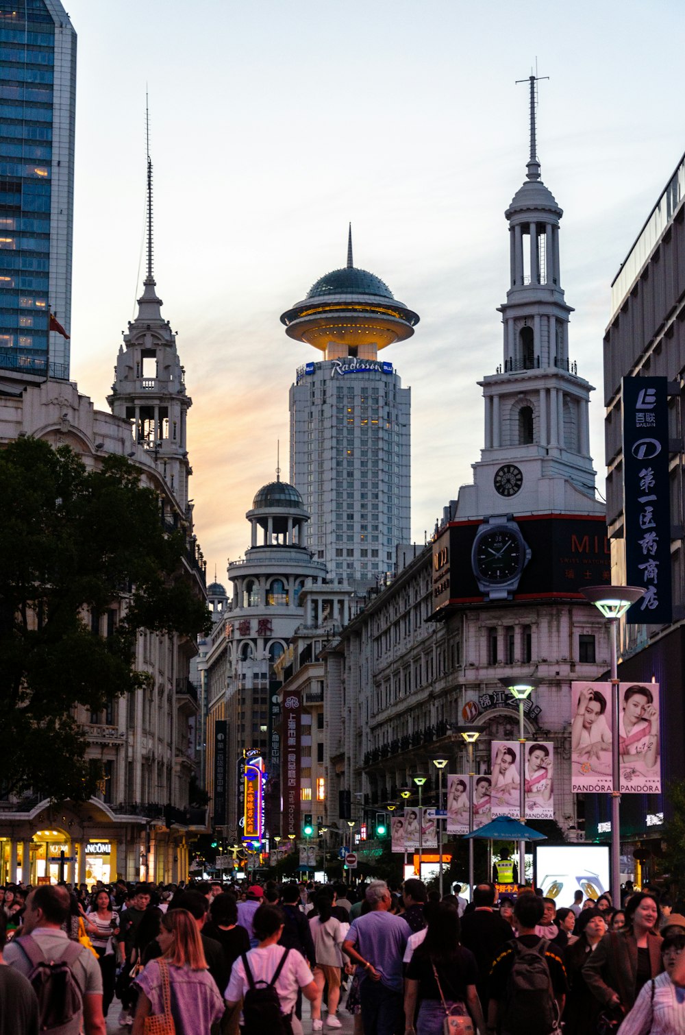 a crowd of people walking down a street next to tall buildings