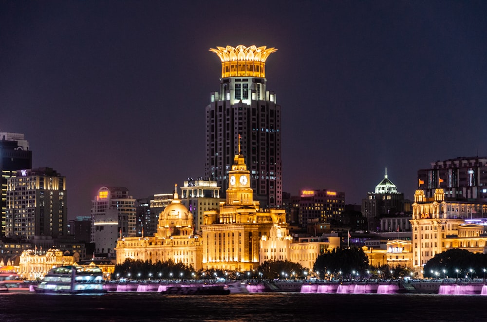 Un horizonte de la ciudad por la noche con una torre del reloj iluminada