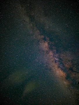A star-filled night sky with a dense cluster of stars forming a bright band across the image, likely representing the Milky Way galaxy. The stars vary in brightness and color, set against a deep, dark background.