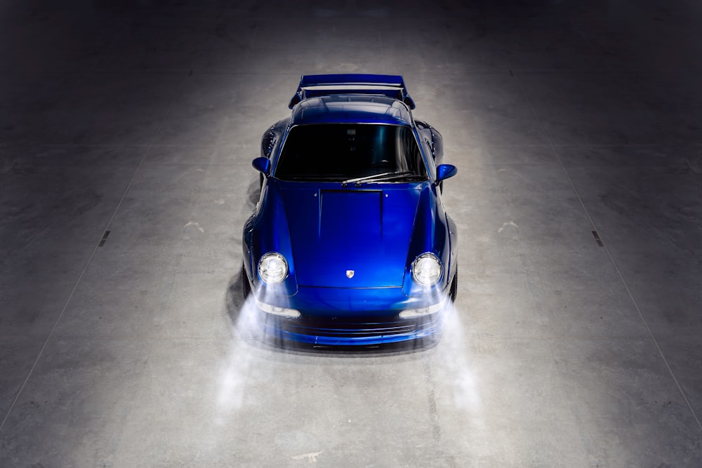 a blue car is parked in a dark room